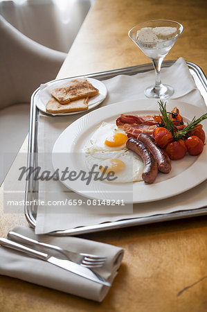 A hearty breakfast featuring fried eggs, sausages, bacon and toast