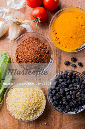 Couscous, black chickpeas, tomatoes, garlic and spices on a wooden table