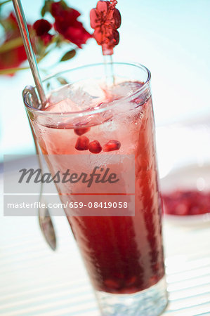 A glass of pomegranate drink with ice cubes