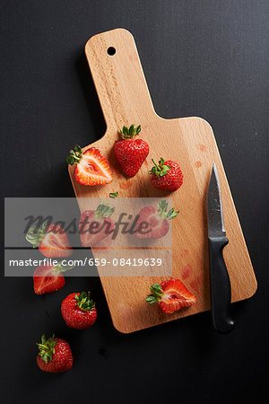 Halved strawberries on a wooden chopping board Halved strawberries on a wooden chopping board