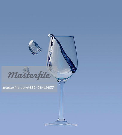 A white wine glass with a splash on a blue background A white wine glass with a splash on a blue background