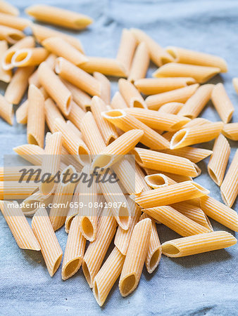 Wholemeal penne pasta on a blue cloth