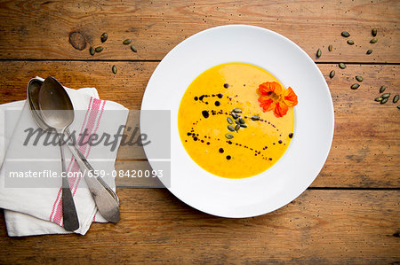 Cream of pumpkin soup with pumpkin seeds, pumpkin seed oil and nasturtium flowers