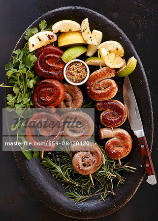 Sausage skewers with lemons on a bed of herbs Sausage skewers with lemons on a bed of herbs