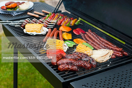 Sausages, skewers and vegetables on a charcoal barbecue Sausages, skewers and vegetables on a charcoal barbecue