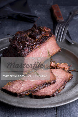 Roast beef studded with rosemary on a pewter plate