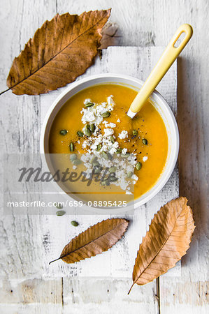A bowl of pumpkin soup with feta cheese and pumkin seeds A bowl of pumpkin soup with feta cheese and pumkin seeds