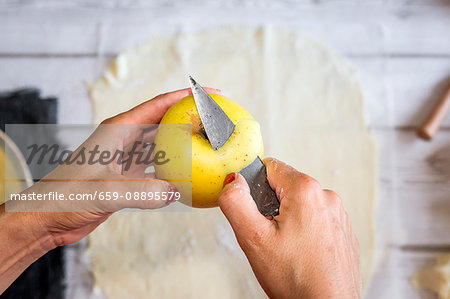 A woman peeling a yellow apple for apple cake
