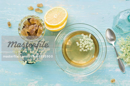 Elderflower tea in a cup, elderflowers, lemon slices and rock sugar Elderflower tea in a cup, elderflowers, lemon slices and rock sugar