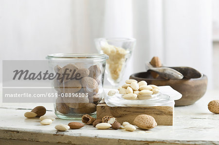 Almonds in and next to a glass jar and a nutcracker on a rustic kitchen table Almonds in and next to a glass jar and a nutcracker on a rustic kitchen table
