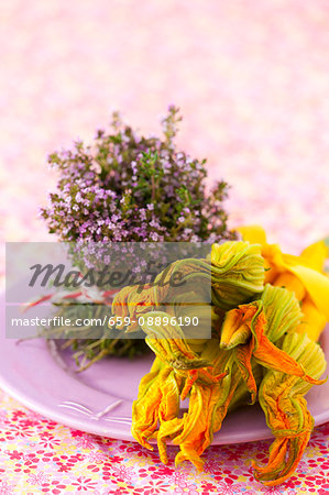 An arrangement of blossoming thyme and yellow courgette with flowers on a plate