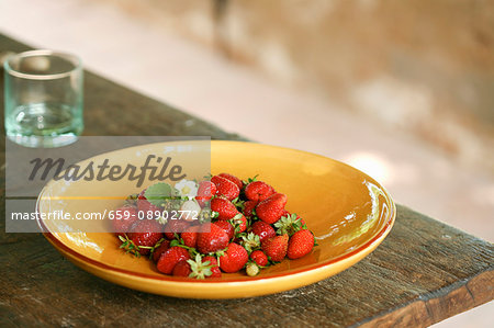 Freshly picked strawberries on a plate on a wooden table outside