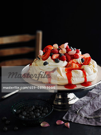 Pavlova With Strawberries Blueberries And Rose Petals Stock Photo