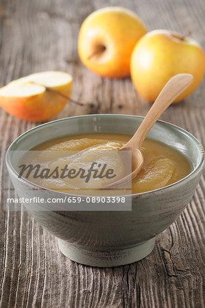 A bowl of apple sauce with a spoon