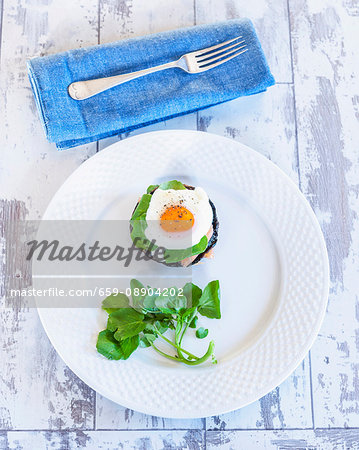 A stack of poached egg and salmon on mushrooms with watercress