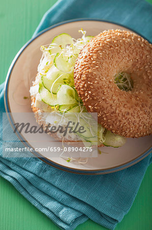 A bagel filled with cucumber, feta cheese and alfalfa sprouts A bagel filled with cucumber, feta cheese and alfalfa sprouts