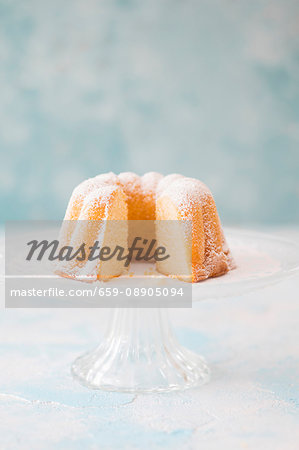 Lemon Bundt cake coated in icing sugar on a cake stand