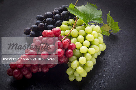 Black, red and green grapes on a black surface