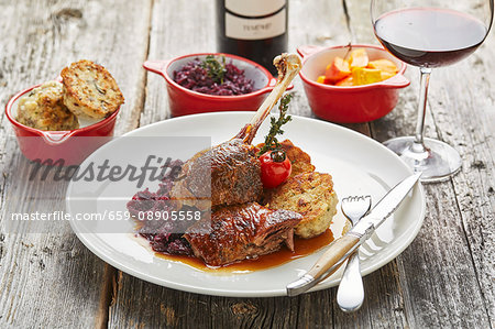 Roast goose with bread dumplings, red cabbage, pumpkin and a glass of red wine