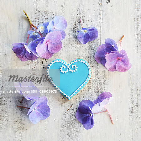 Heart-shaped biscuits decorated with blue and white icing and surrounded by flowers