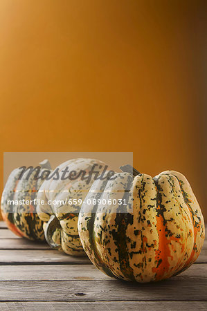 An arrangement of three pumpkins against an orange background