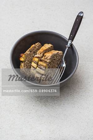 Three slices of gluten-free banana bread with chia seeds in a bowl