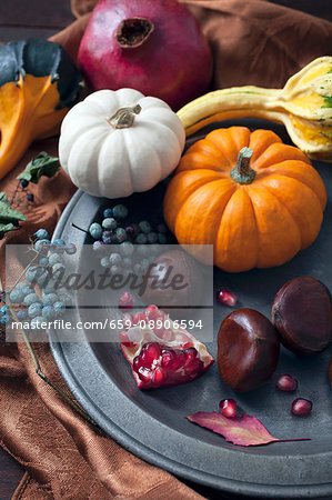 An autumnal arrangement of pumpkins, chestnuts, pomegranates and berries An autumnal arrangement of pumpkins, chestnuts, pomegranates and berries