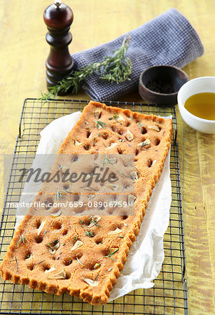 Vegan focaccia with dried tomatoes, garlic and herbs on a cooling rack