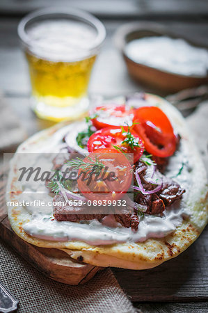 Pita bread topped with beef, cream cheese, tomatoes and onions