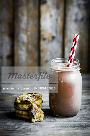 Chocolate milk in a jar with a straw with cookies next to it