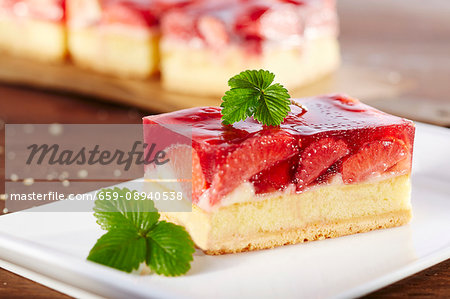 A slice of strawberry cake garnished with a strawberry leaf