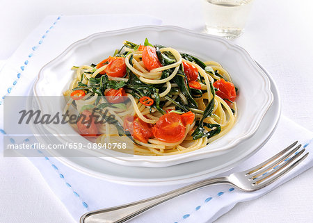 Fried spaghetti with dandelions, tomatoes and chilli