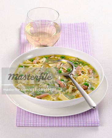 Noodle soup with peas and strips of ham