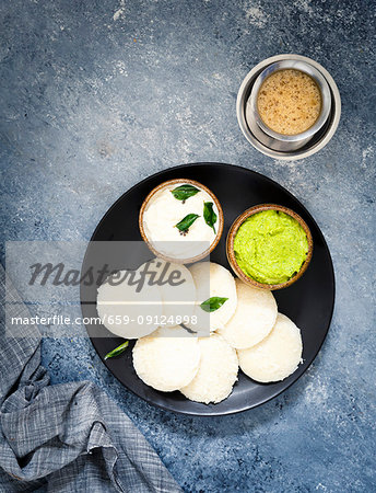 Traditional breakfast with Idli (rice cakes), coriander chutney, coconut chutney and coffee (South India)