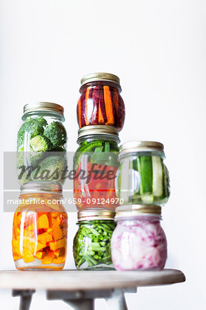 Preserving jars of freshly pickled vegetables stacked on an old stool