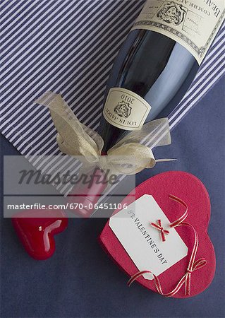 Wine bottle tied with ribbon and a heart-shaped gift box Wine bottle tied with ribbon and a heart-shaped gift box