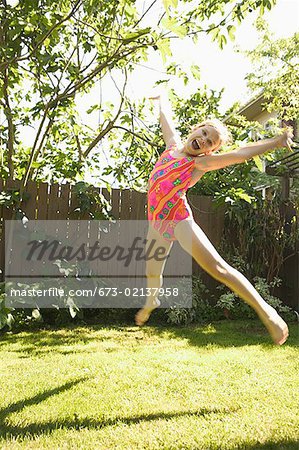 Young girl in a swimming suit leaping in the air.
