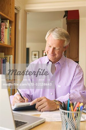 Man writing checks in his home office.