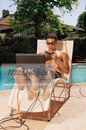 A teenaged boy playing video games poolside