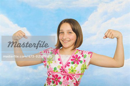 A teenaged girl flexing her muscles - Stock Photo - Masterfile