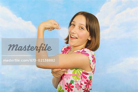 Woman flexing biceps and smiling - Stock Photo - Masterfile