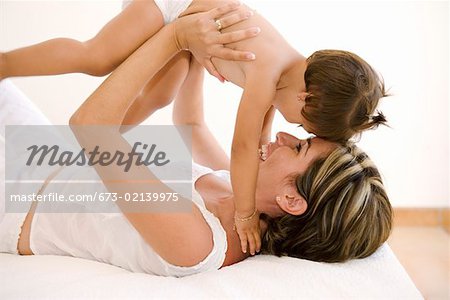 Mother playing with toddler on bed