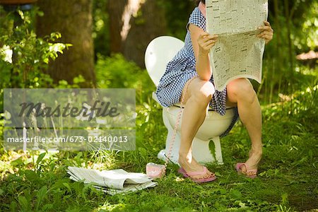 Woman sitting on toilet in forest