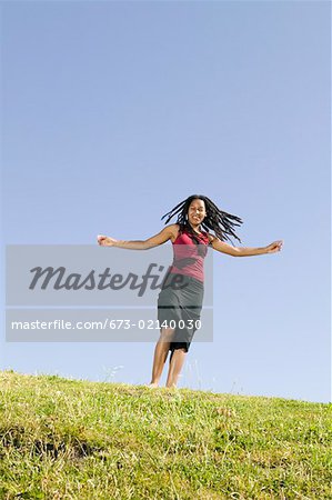 Young woman running on grassy hill