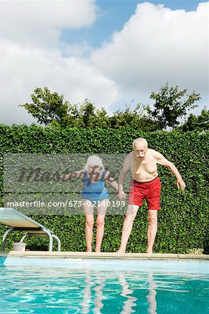 Senior couple preparing to dive into pool