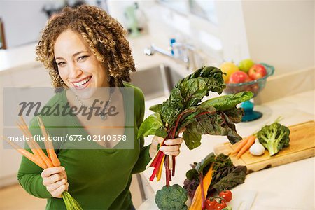 Portrait of woman with vegetables in kitchen