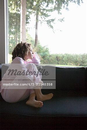 Woman in pajamas looking out window