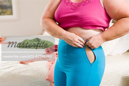 Overweight woman squeezing into small pants