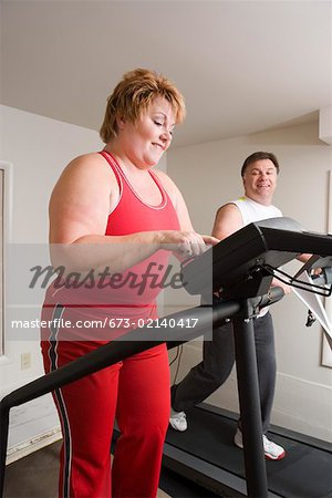 Overweight couple using exercise machines