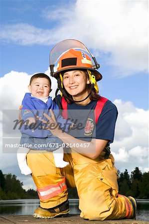 Portrait of female firefighter holding baby